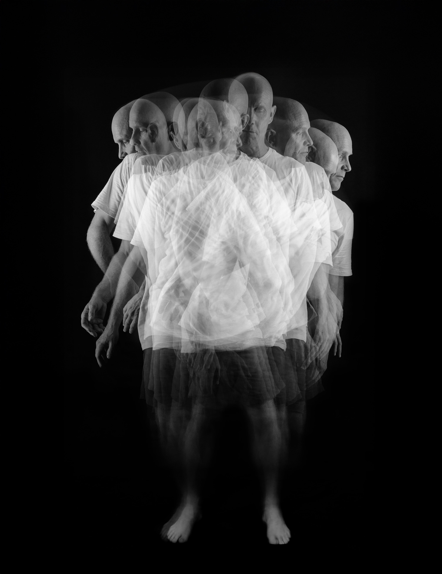 Multiple-exposure portrait of a bald man standing, layered with ghostly repetitions of his movement